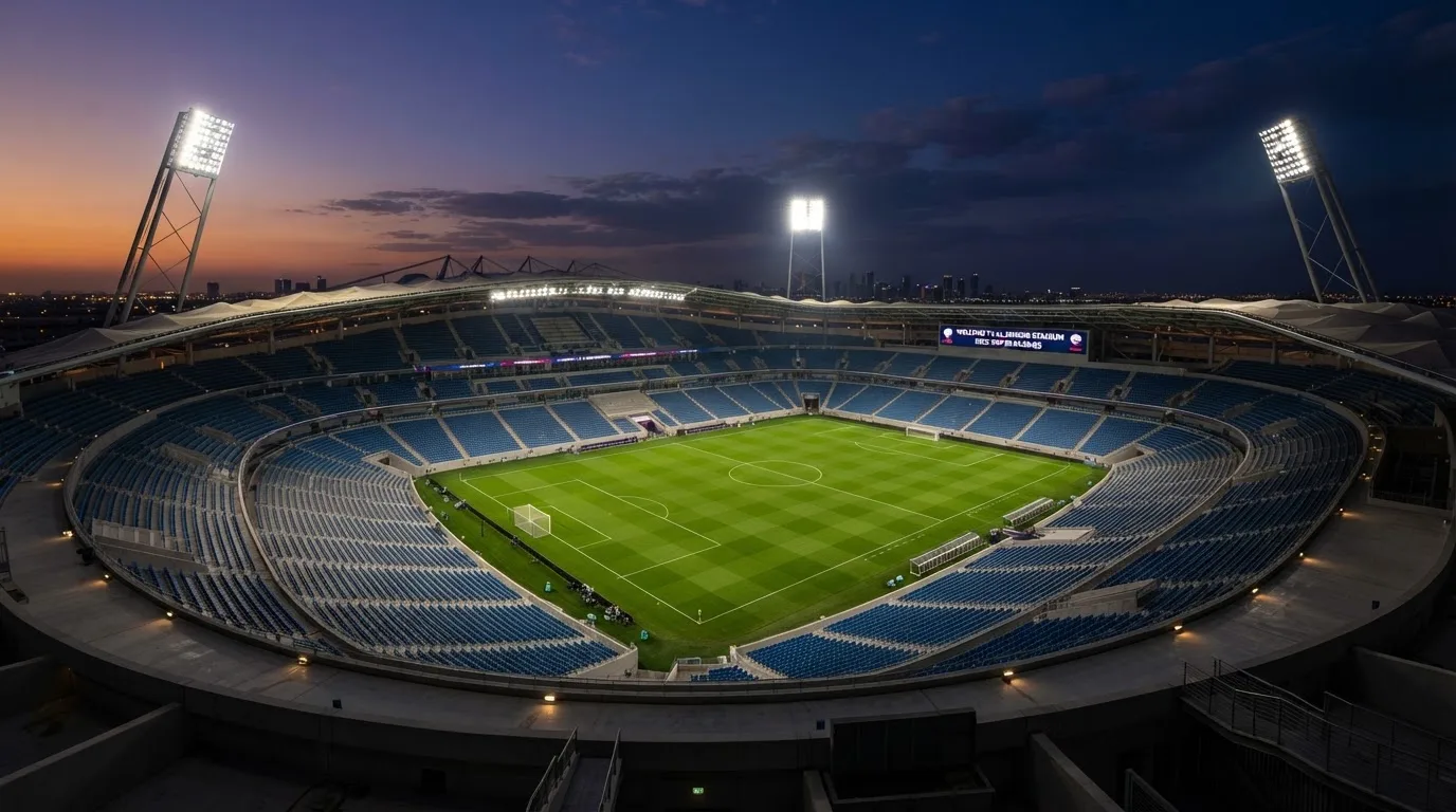 An empty football stadium with floodlight masts at dusk