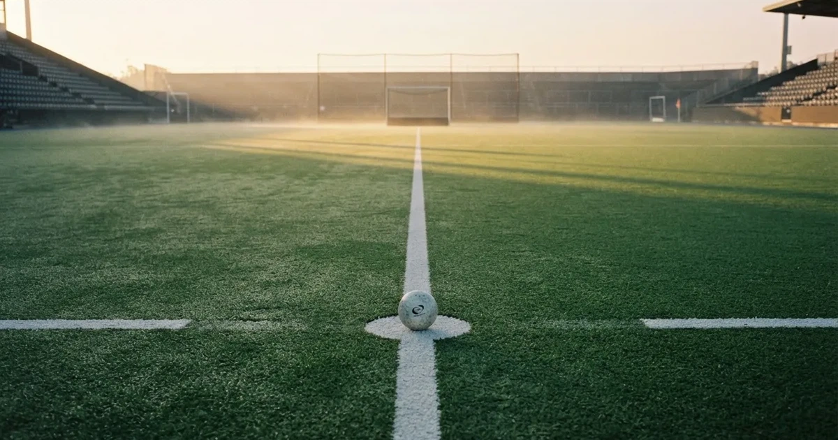 A ball on the centre spot of a grass pitch in morning light