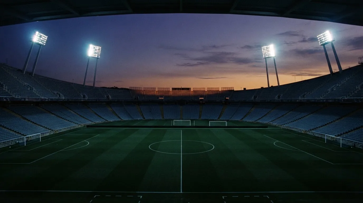 An empty football stadium with floodlight masts at dusk