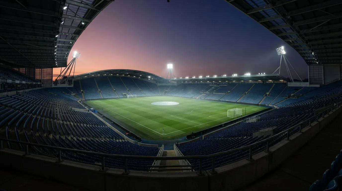 An empty football stadium with floodlight masts at dusk