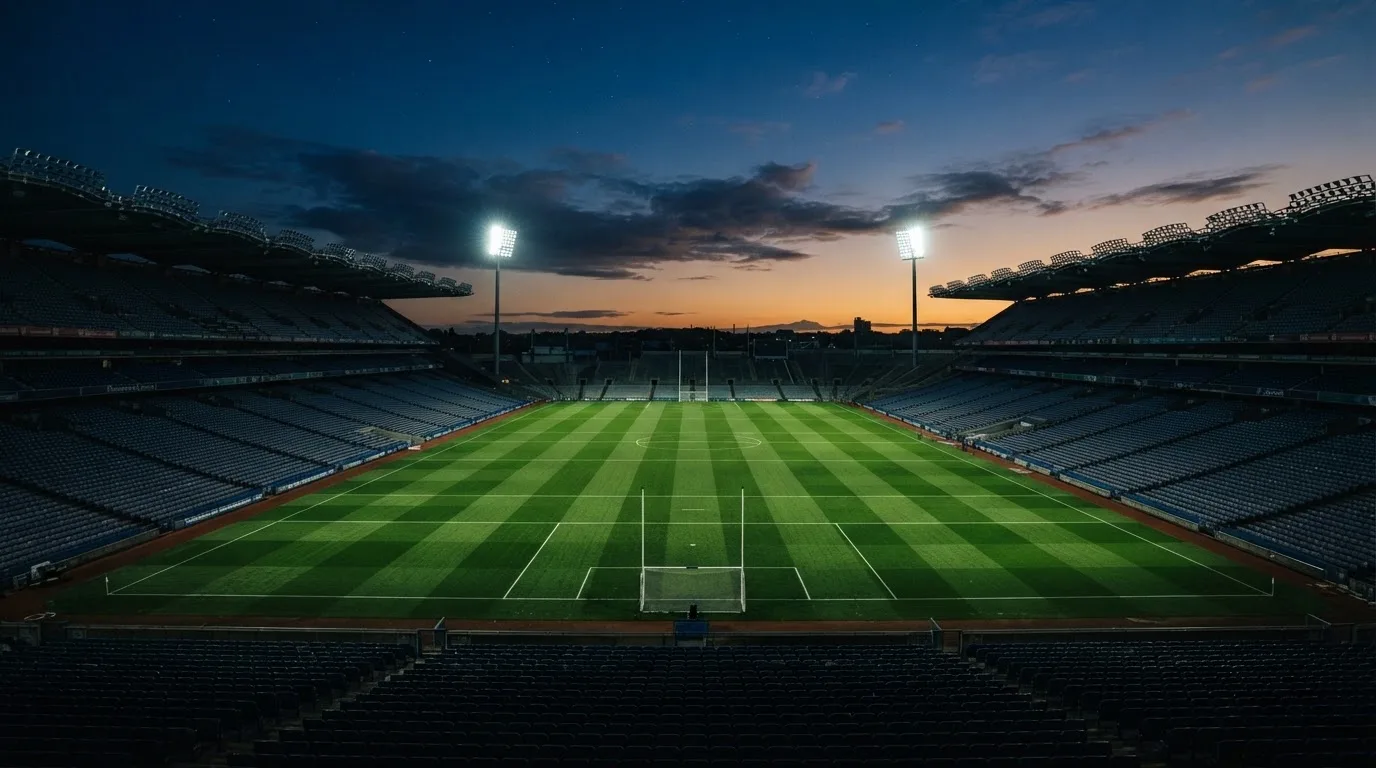 An empty football stadium with floodlight masts at dusk