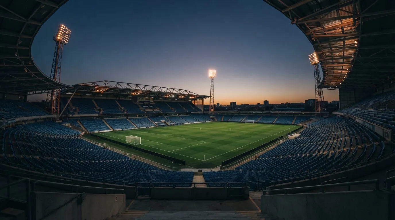 An empty football stadium with floodlight masts at dusk