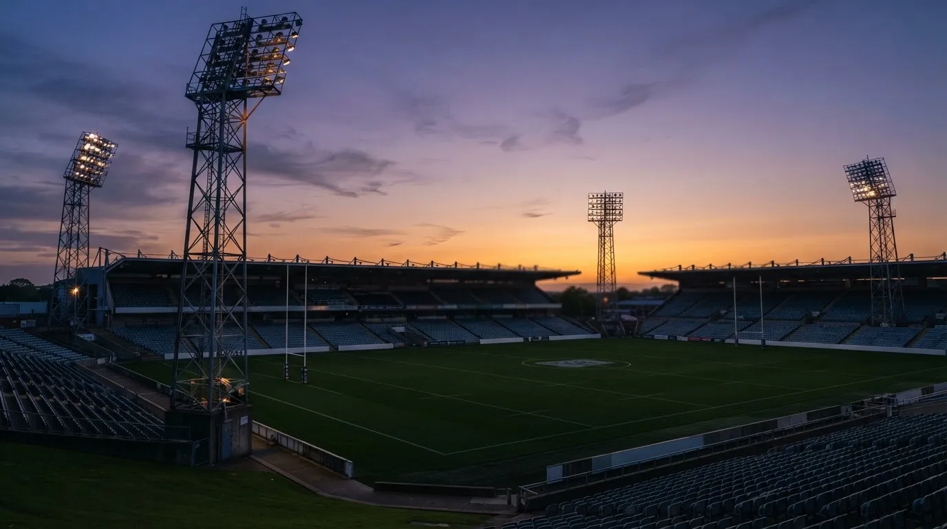 An empty football stadium with floodlight masts at dusk