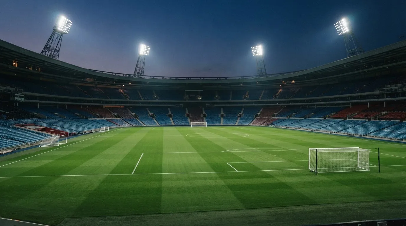 An empty football stadium with floodlight masts at dusk