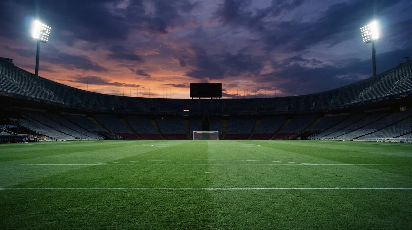 An empty football stadium with floodlight masts at dusk
