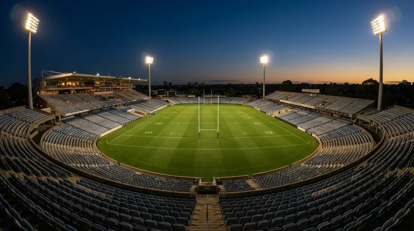 An empty football stadium with floodlight masts at dusk