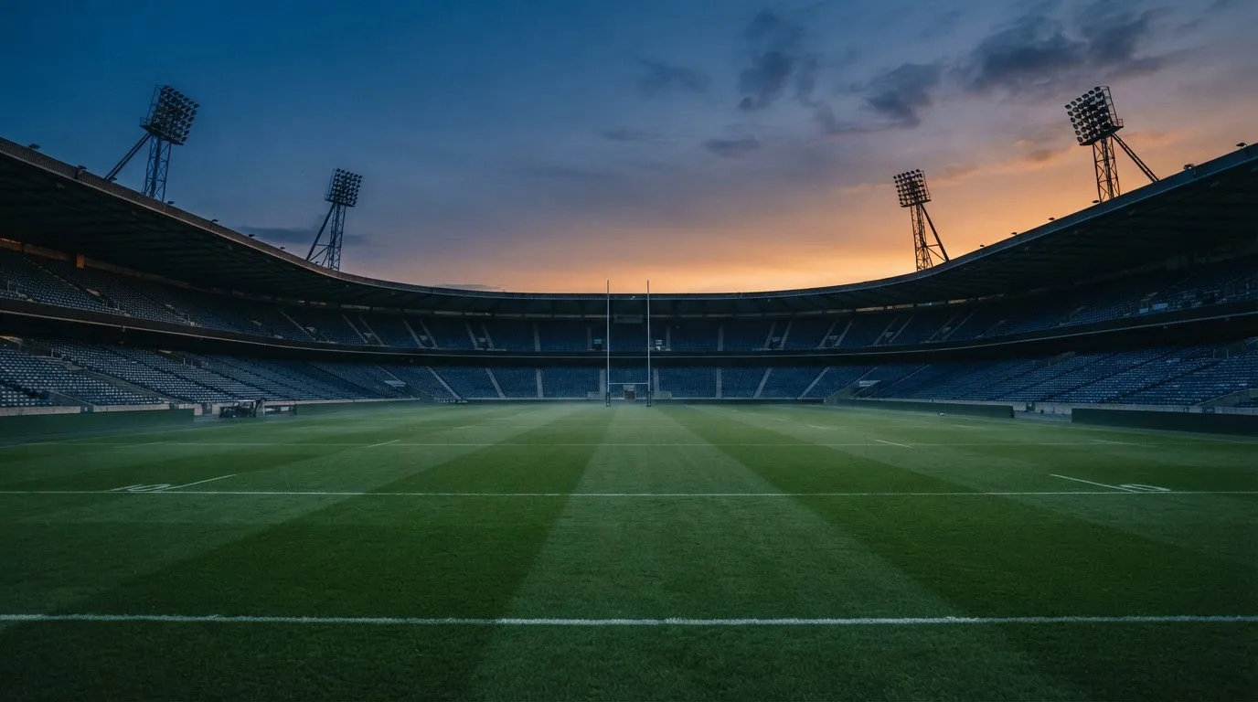 An empty football stadium with floodlight masts at dusk