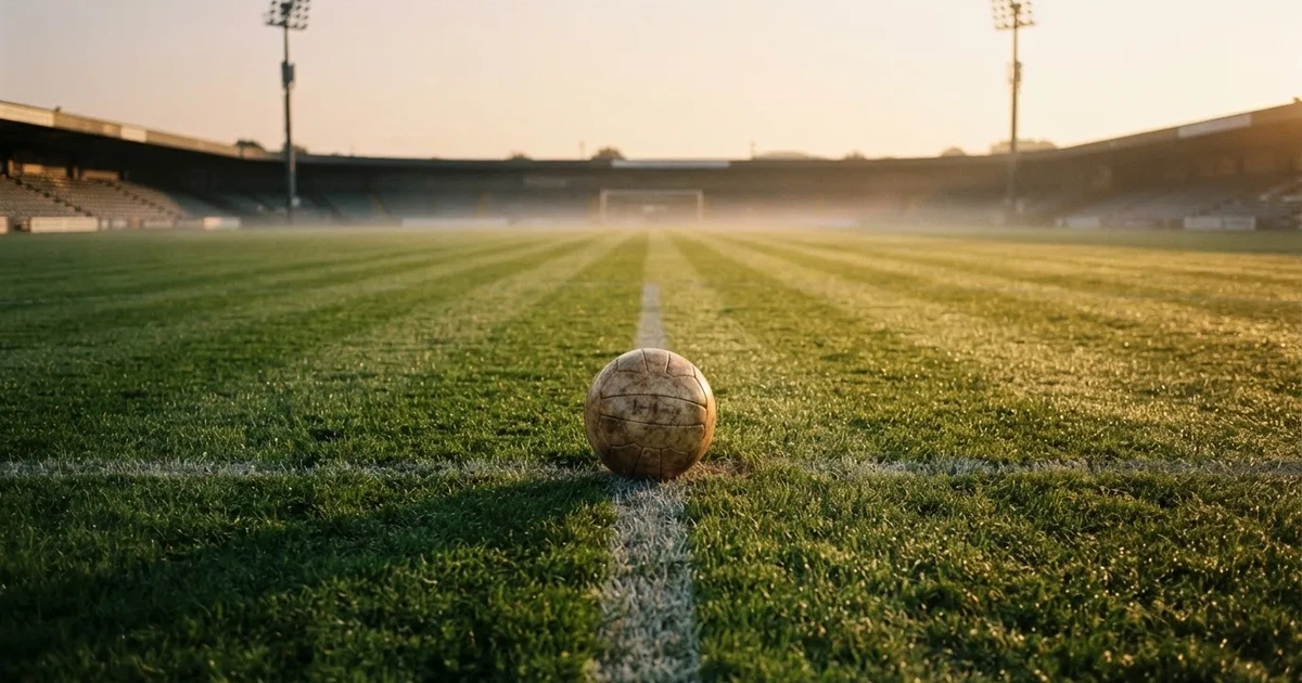 A ball on the centre spot of a grass pitch in morning light