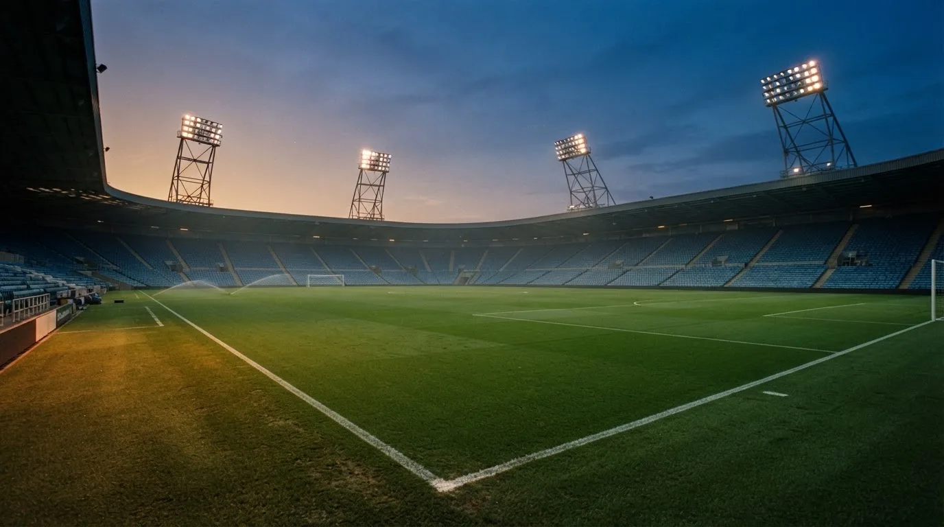 An empty football stadium with floodlight masts at dusk