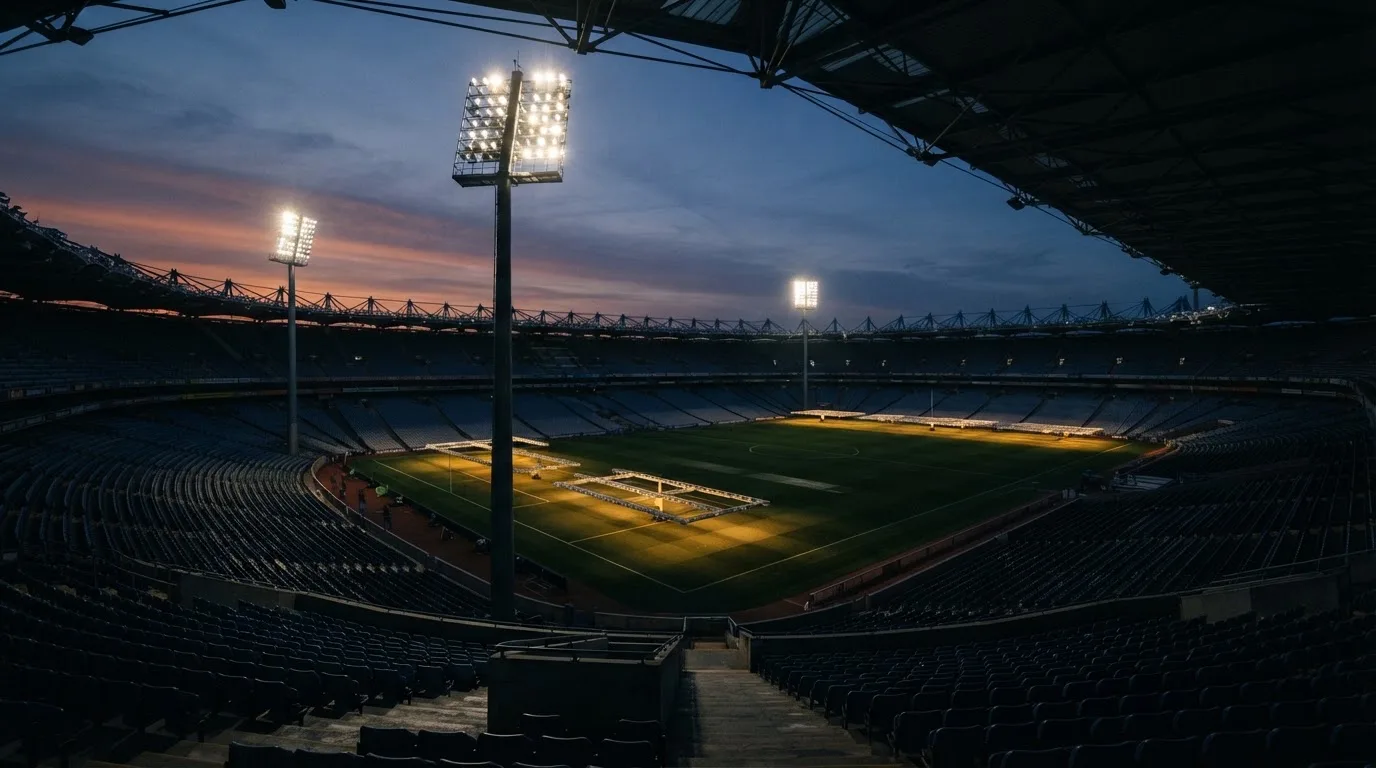 An empty football stadium with floodlight masts at dusk