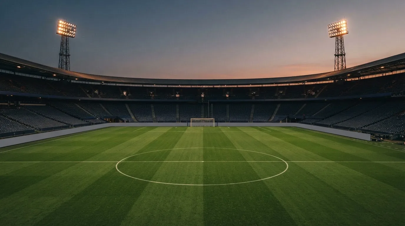 An empty football stadium with floodlight masts at dusk