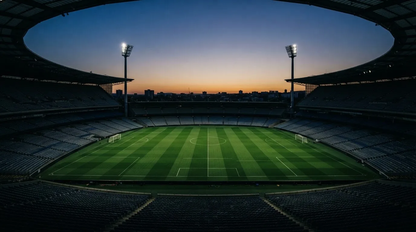 An empty football stadium with floodlight masts at dusk