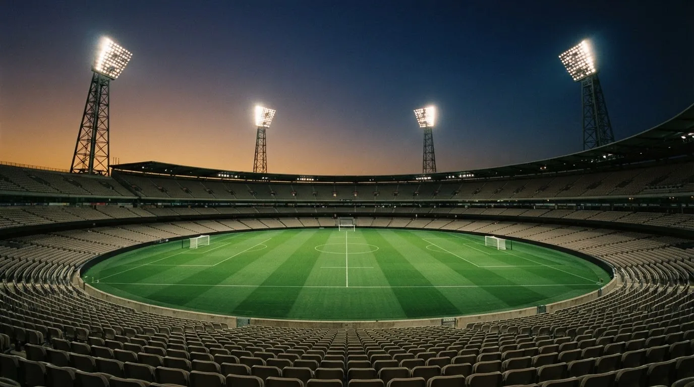 An empty football stadium with floodlight masts at dusk